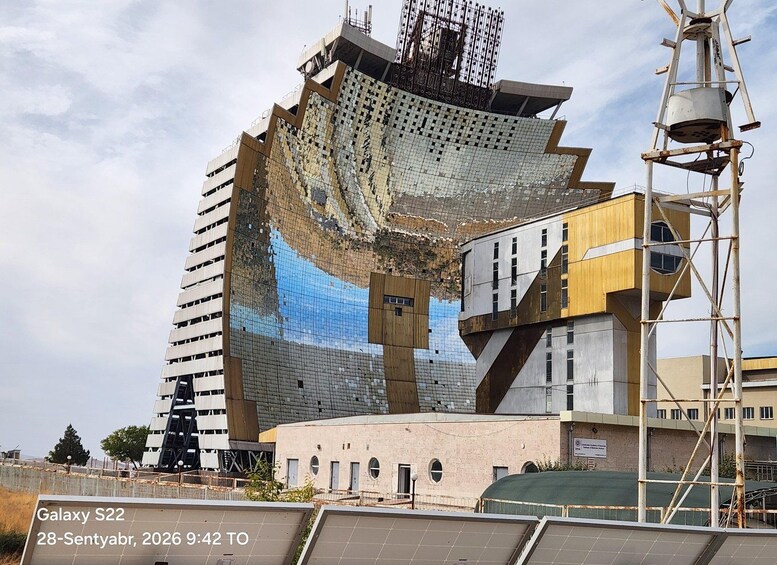 A modern building with a unique facade, solar panels, and construction scaffolding. 2