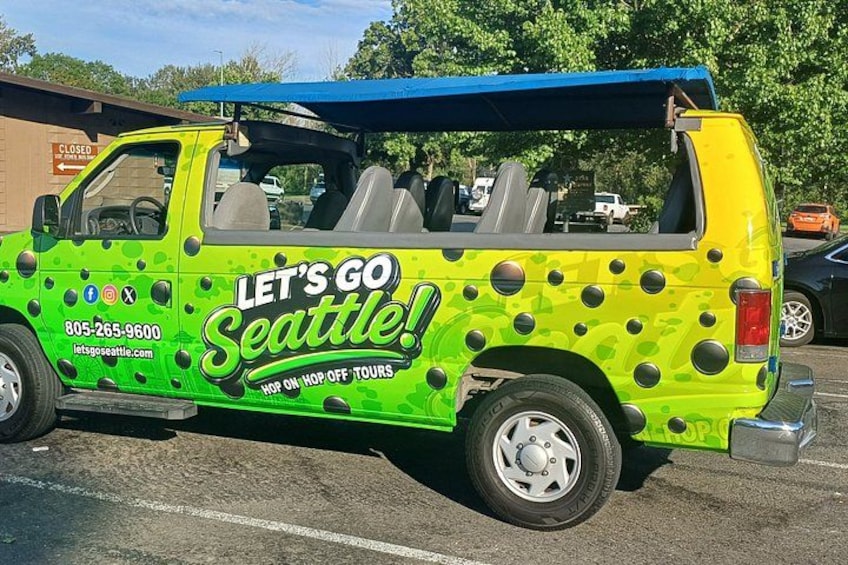 A green and yellow van with 'LET'S GO SEATTLE!' written on the side, parked in a lot. 1