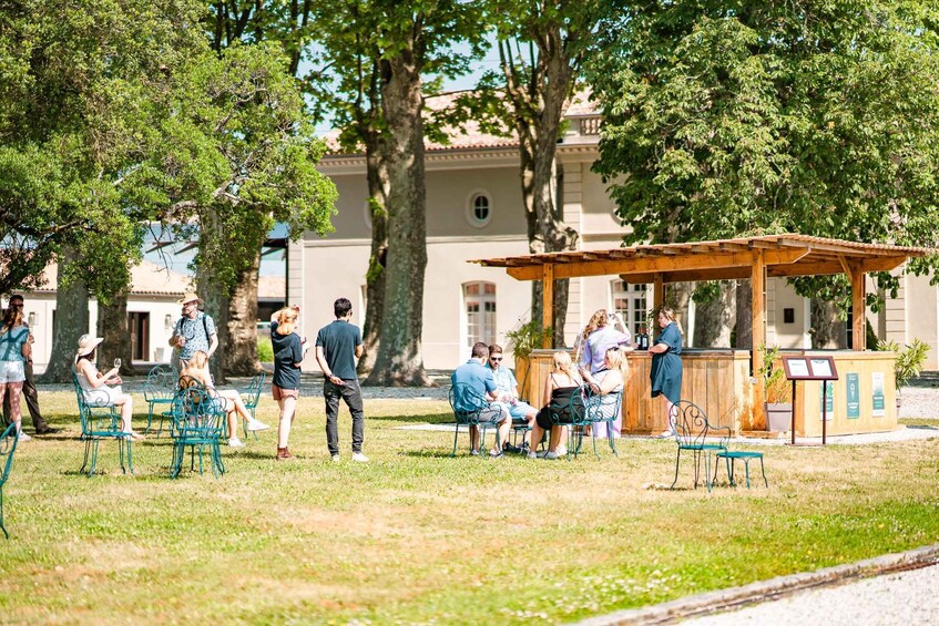 A park with people sitting at tables, a wooden gazebo, and a building in the background. 3
