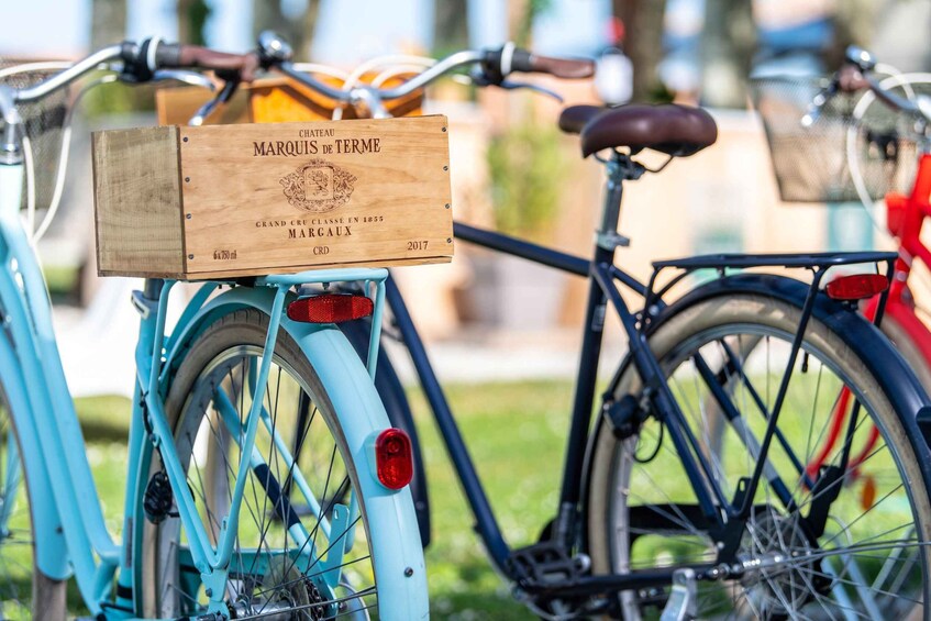 A blue bicycle with a wooden sign attached to the rear, indicating it is a Marquis de Terme Grand Cru Classe En 1855 Margaux. 1