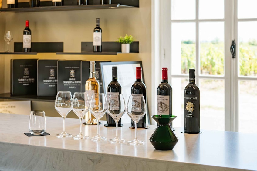A wine tasting setup with several wine bottles and glasses on a counter. 5