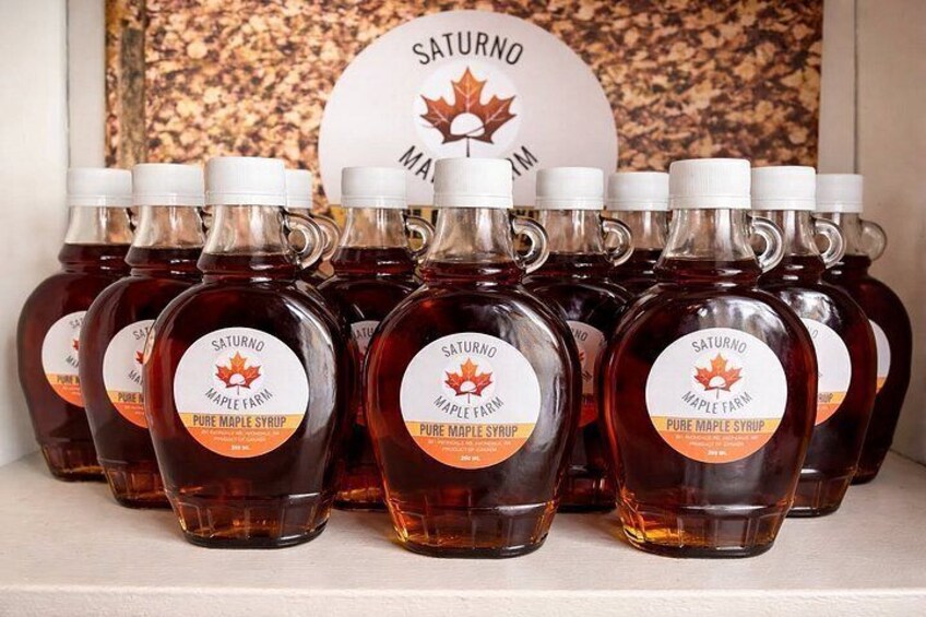Multiple bottles of maple syrup with labels, arranged on a shelf. 4