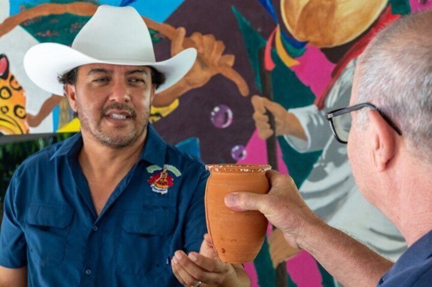 A person in a blue shirt and white cowboy hat holding a clay pot. 5