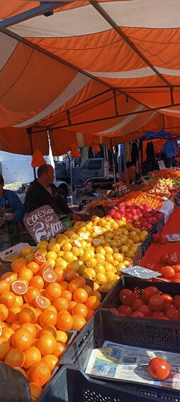 A fruit market with oranges and apples under an orange canopy. 3