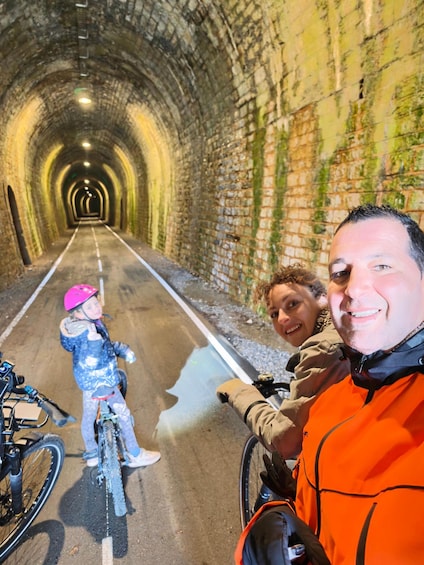 A tunnel with brick walls and a cyclist wearing a pink helmet. 1