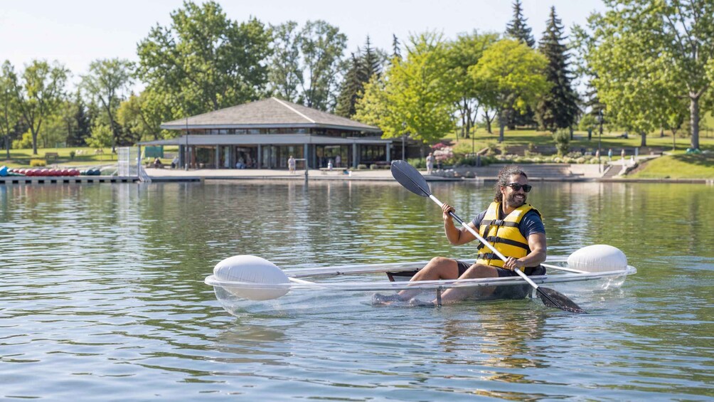 A person kayaking on a calm lake with a pavilion in the background. 2