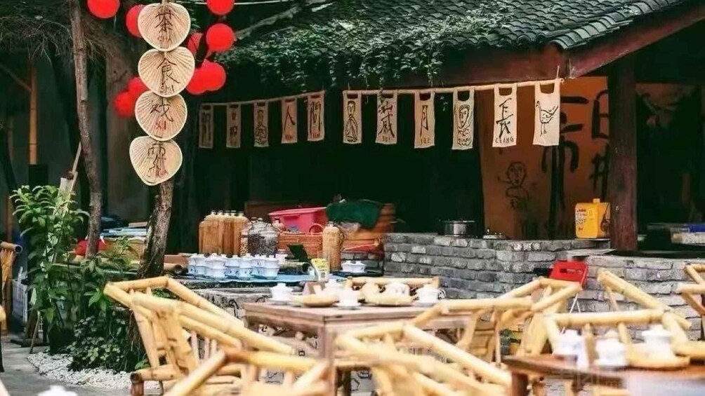 A traditional outdoor dining area with bamboo furniture and hanging lanterns. 2