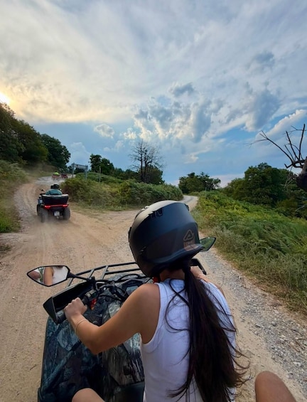 A person riding a quad bike on a dirt road with a cloudy sky. 1