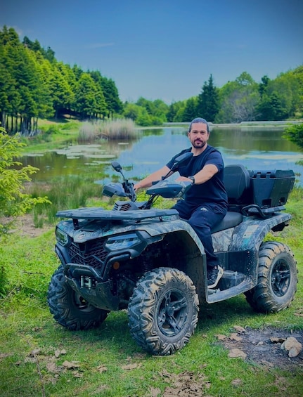 A person on an all-terrain vehicle (ATV) in a natural setting with a lake and greenery. 3