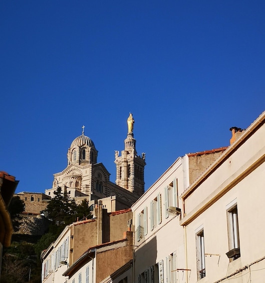 A historic church with a dome and a statue on a hill, surrounded by buildings. 1