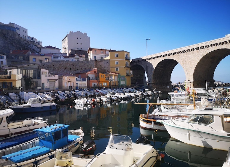 A harbor with boats docked, a stone bridge, and colorful buildings. 4