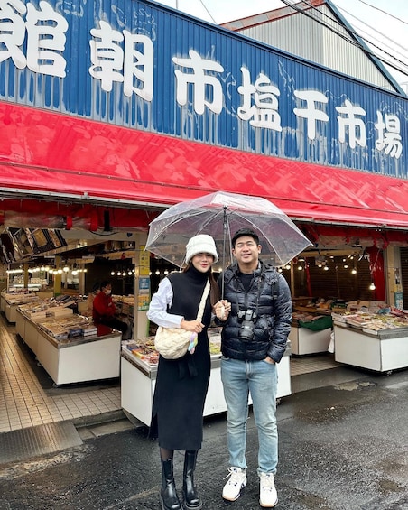 A market with a blue and red awning, and a sign with white characters. 1