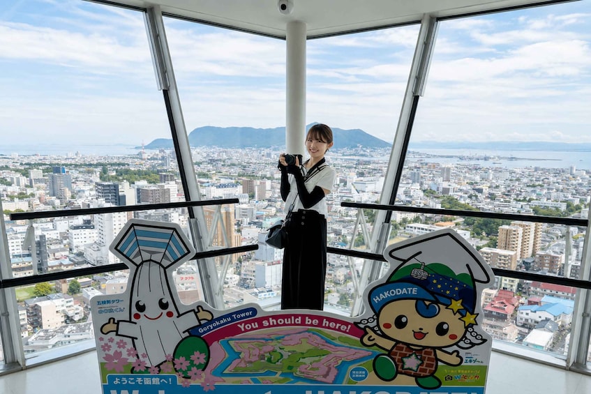 A person taking a photo with a view of a cityscape and mountains in the background. 4
