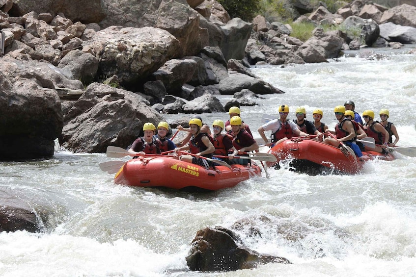 A group of people rafting on a river with rocks and rapids. 1