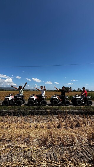 Four people on ATVs in a field with a clear sky. 3