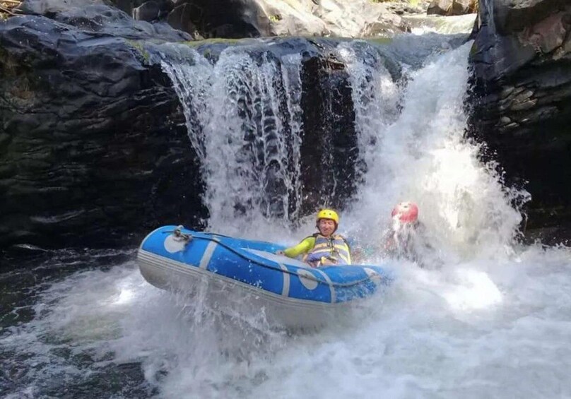 A person in a blue inflatable raft navigating a waterfall. 5