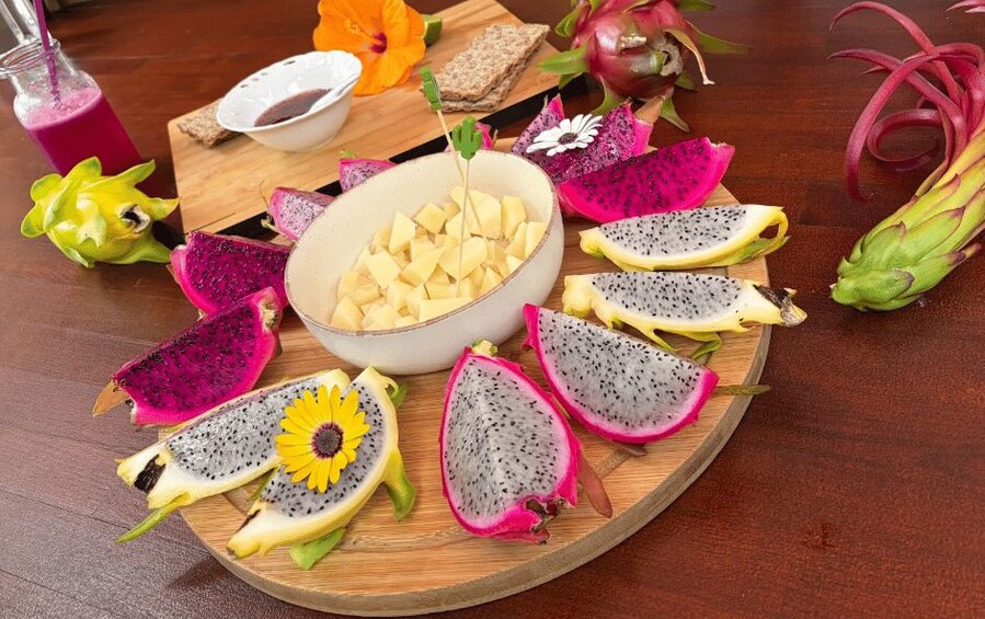 A wooden board with dragon fruit halves, a bowl of diced fruit, and a glass of pink smoothie. 2