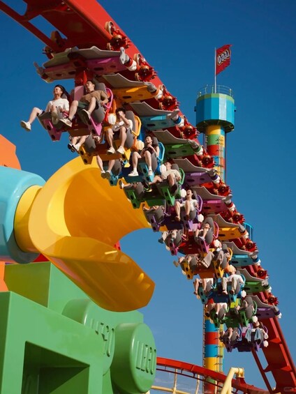 A colorful roller coaster with multiple cars and riders. 5