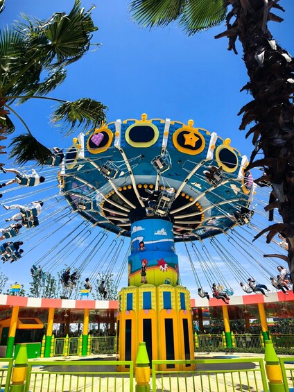 A colorful amusement ride with a large circular top and seats attached by ropes. 3