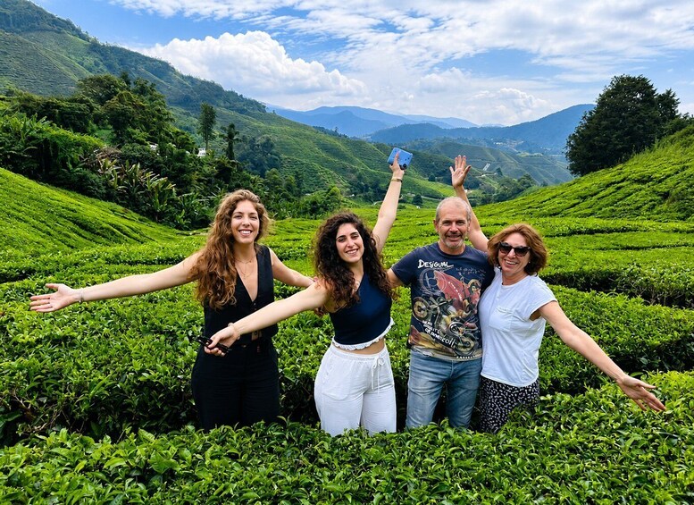 A group of people standing in a lush green tea plantation with rolling hills in the background. 4