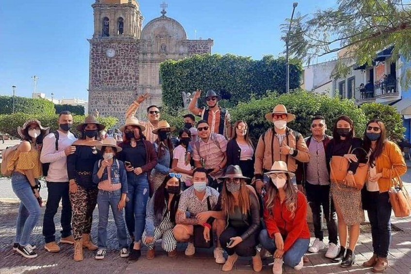 A group of people posing in front of a historic building with a bell tower. 2