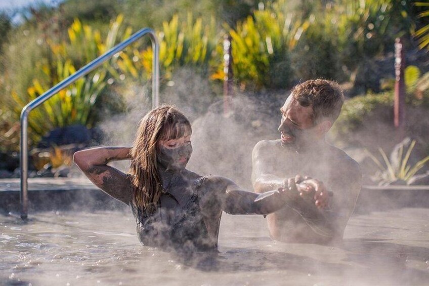 Two people in a hot spring with steam rising around them. 1