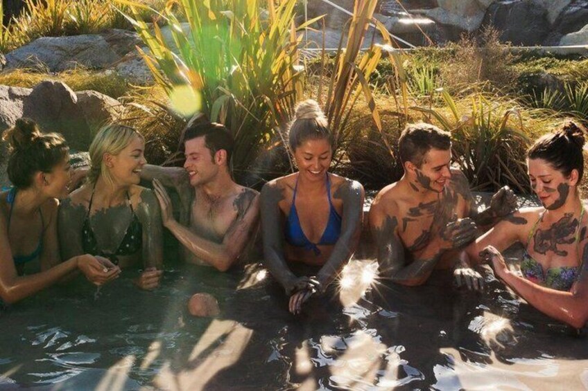 A group of people in a natural setting with water, rocks, and vegetation. 3