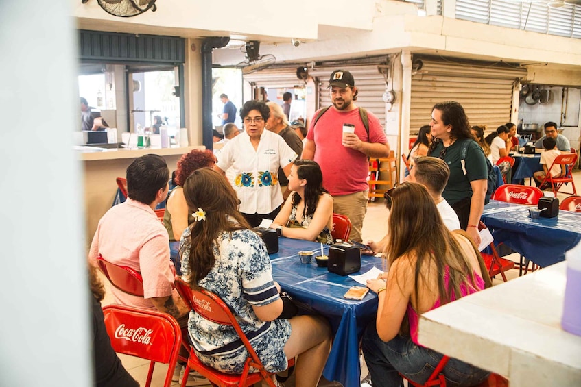 A group of people sitting at tables in a casual dining setting with Coca-Cola branded chairs. 1