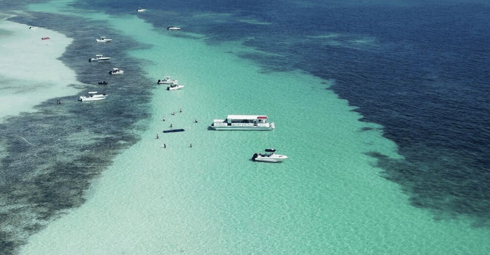 A coastal area with clear turquoise waters, several boats, and a large floating structure. 2