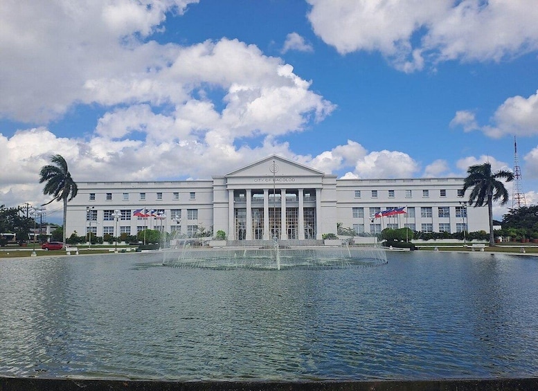 A large building with a central fountain, palm trees, and a clear sky. 4