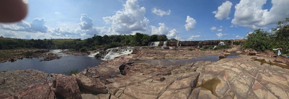 A rocky landscape with a waterfall, a river, and a person washing clothes. 5