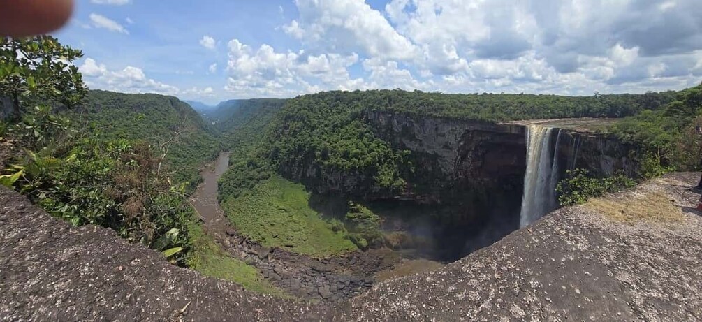 A waterfall cascading down a cliff surrounded by lush greenery. 1