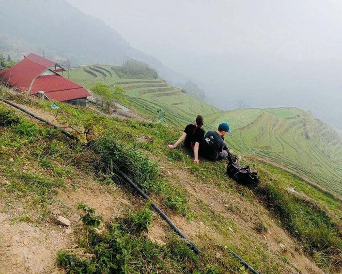 Two people on a hillside with a red-roofed building in the background. 5