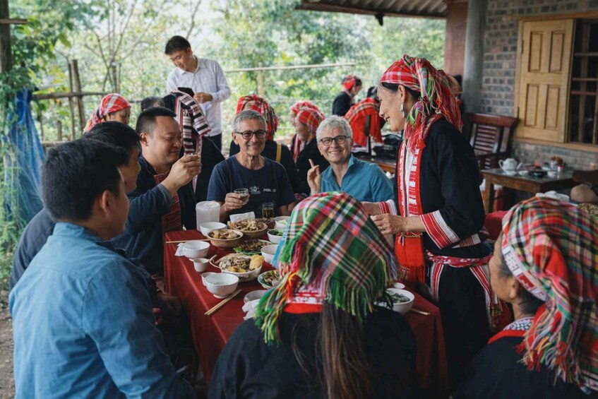 A group of people gathered around a table with food, wearing traditional attire with red and green headscarves. 4
