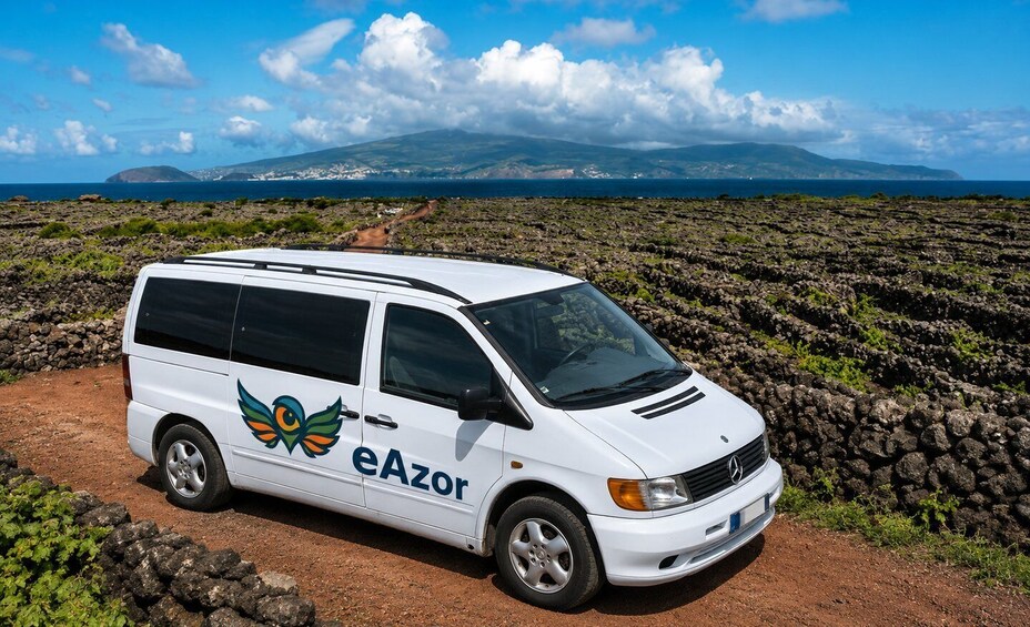 A white van with 'eAzor' branding parked on a rocky terrain with a mountainous backdrop. 1
