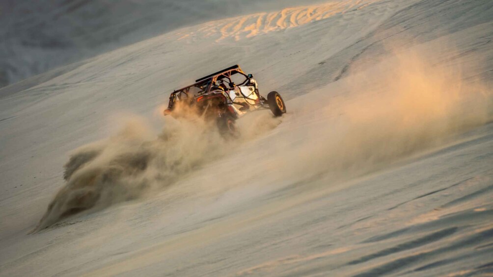 A vehicle navigating a snowy slope, kicking up snow and creating a dust cloud. 5