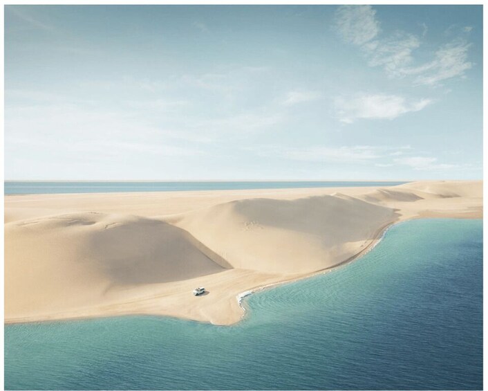 A desert landscape with sand dunes and a body of water. 2