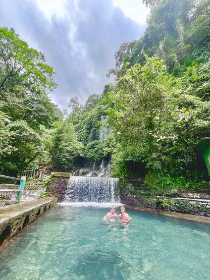 A waterfall cascading into a clear pool surrounded by lush greenery. 1