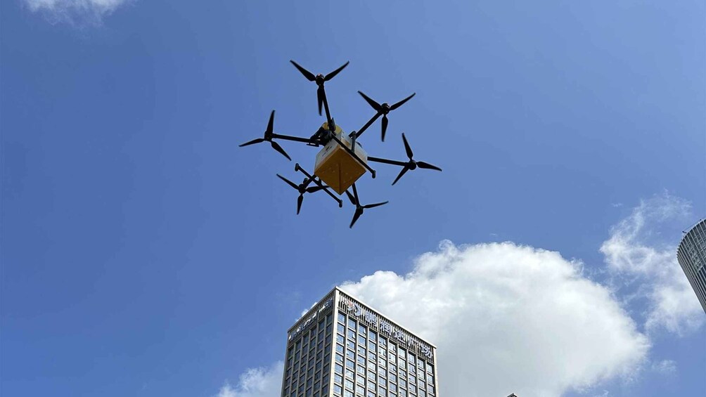 A quadcopter drone flying in the sky with a building in the background. 1
