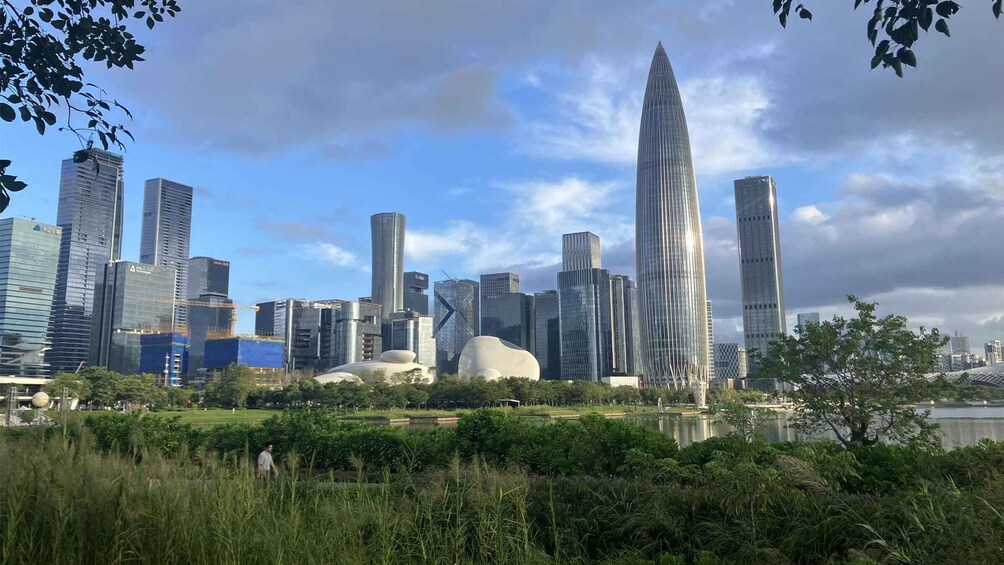 A city skyline with modern skyscrapers, a large water body in the foreground, and a park with greenery. 5