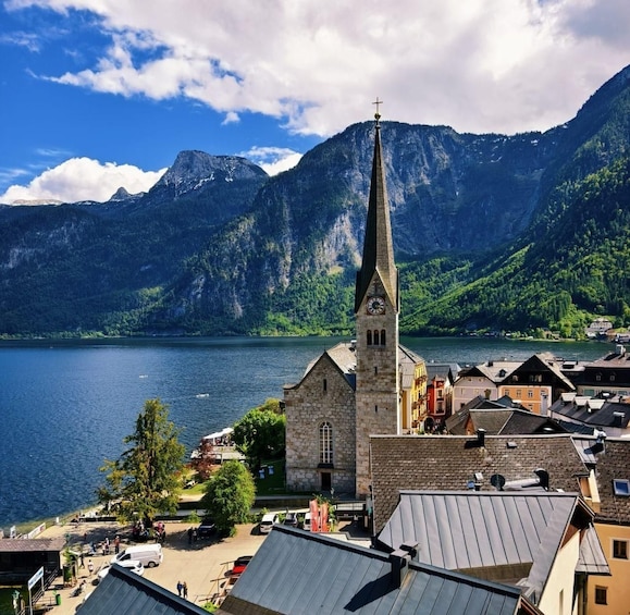 A church with a tall steeple, a lake, and mountains in the background. 4