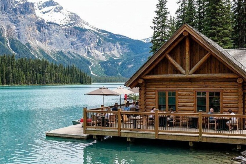 A wooden cabin with a dock extending into a lake, surrounded by mountains and trees. 3
