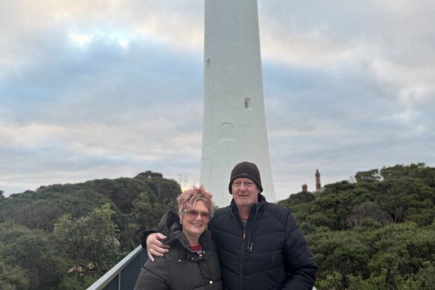 Two people standing in front of a tall monument with a cloudy sky in the background. 3