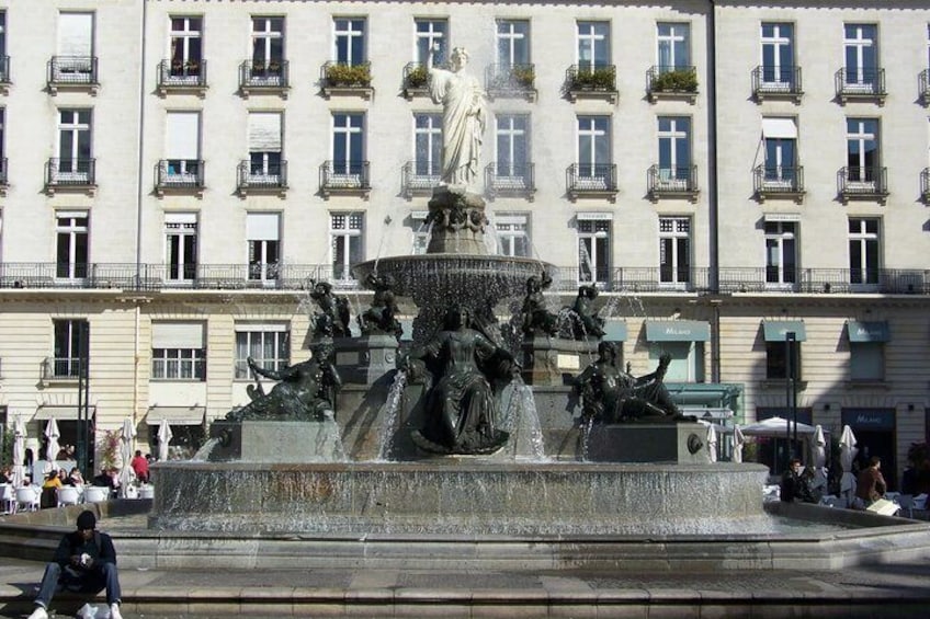 A large fountain with statues in the center, surrounded by a plaza with buildings in the background. 4