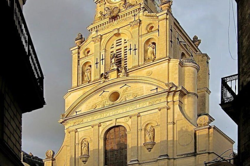 A historic church with a bell tower, arched windows, and statues. 5