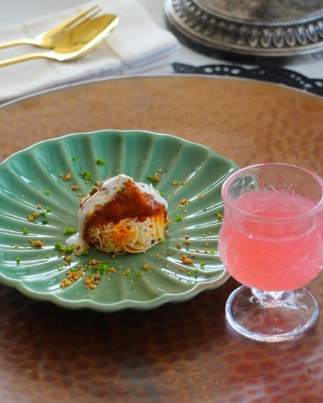 En grøn tallerken med dessert og en pink drik på et bord. 2
