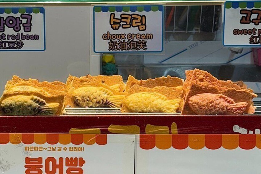 A food stall with signs in a foreign language, displaying various food items. 5