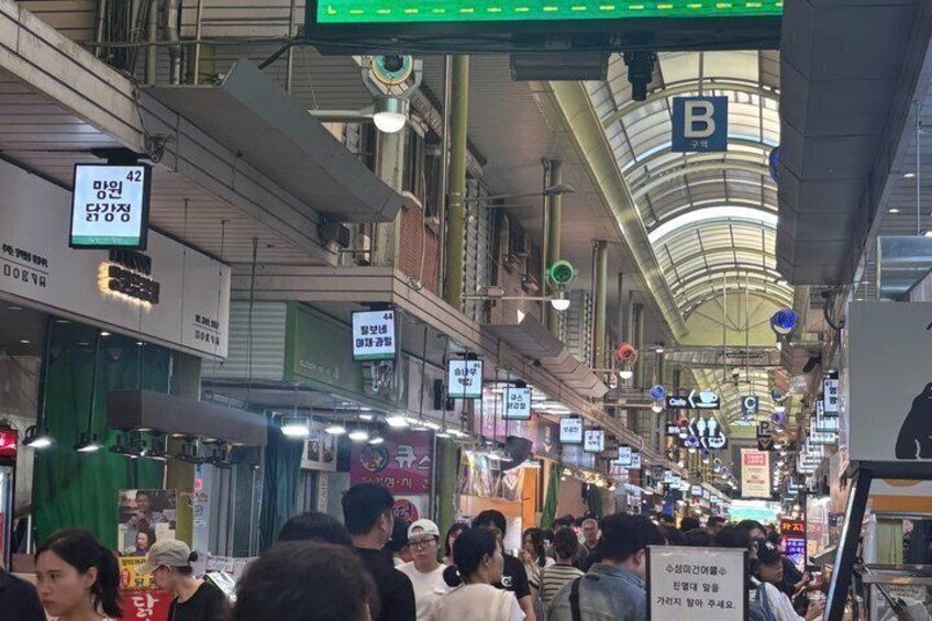 A busy indoor market with various shops and signs. 3