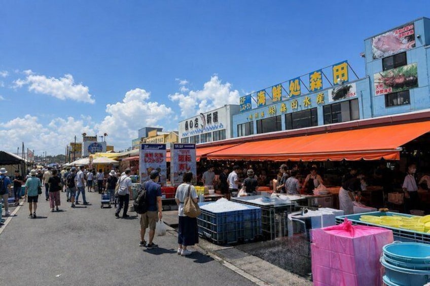 A busy outdoor market with people shopping and vendors selling goods. 5
