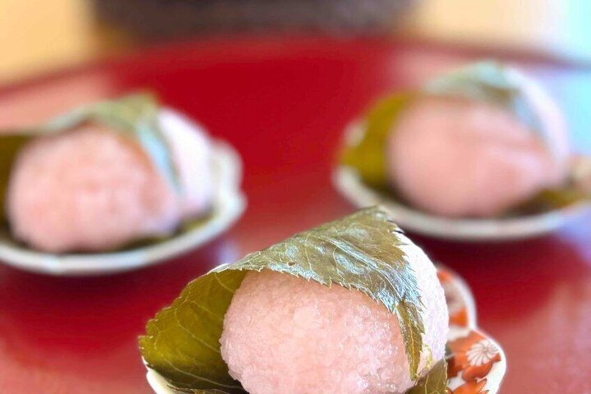 A close-up of a food item wrapped in a leaf, with a blurred background. 3